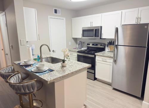 a kitchen with white cabinets and a stainless steel refrigerator at Apartment in Houston near NRG with Free Parking in Houston