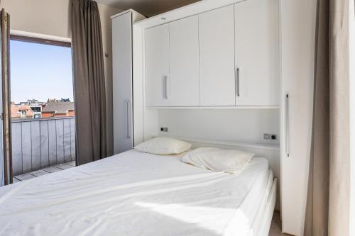 a bedroom with a white bed and a window at Shangri-La 0202 G in Sint-Idesbald