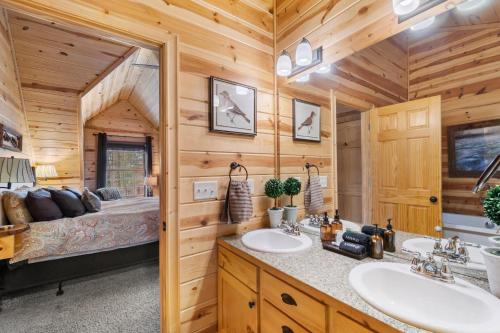 une salle de bain de chalet en rondins avec deux lavabos et un lit dans l'établissement The Timber Nest Goshorn lake dock pool town, à Saugatuck