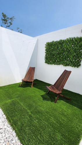 two wooden chairs sitting on the grass next to a wall at Casa 3 recamaras con alberca compartida Acapulco diamante in General Juan N Alvarez International Airport