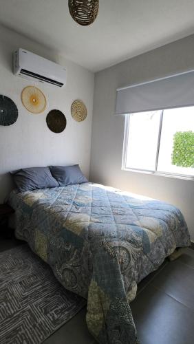 a bedroom with a bed with a comforter and a window at Casa 3 recamaras con alberca compartida Acapulco diamante in General Juan N Alvarez International Airport