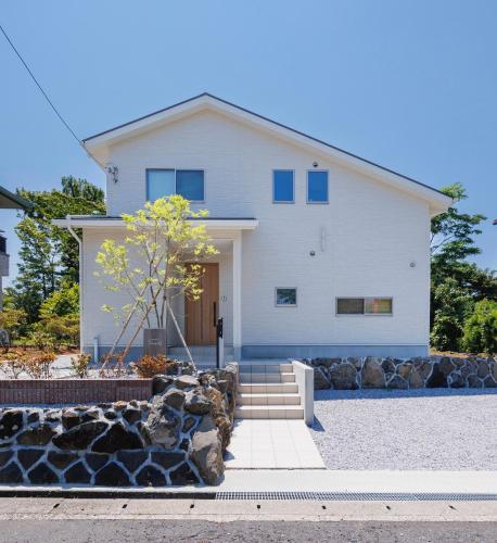 a white house with blue windows at New Villa Natural Q 城ケ崎海岸 伊豆高原 in Ito