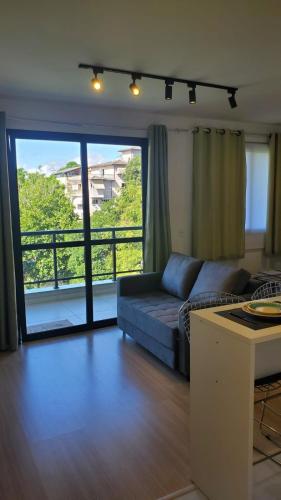a living room with a couch and a large window at Lindo Studio Aconchegante no Ingá in Niterói