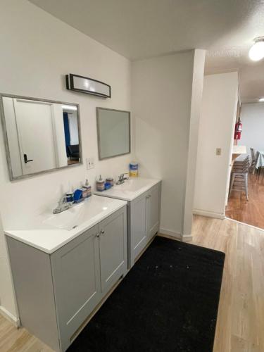 a white bathroom with two sinks and a mirror at Alaska Backpacker Hostel in Anchorage