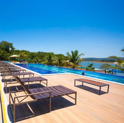 une piscine avec des bancs et une vue sur l'eau dans l'établissement Resort do Lago consulte dias disponíveis, à Caldas Novas