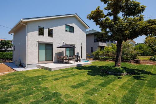 a house with a tree in the yard at New Villa Natural Q 城ケ崎海岸 伊豆高原 in Ito