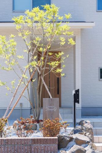 a tree in front of a building with a sign at New Villa Natural Q 城ケ崎海岸 伊豆高原 in Ito