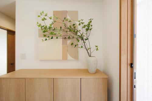 a vase on top of a wooden cabinet with a plant at New Villa Natural Q 城ケ崎海岸 伊豆高原 in Ito