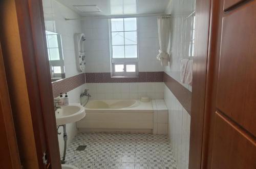 a white bathroom with a tub and a sink at Gwangju M Motel in Gwangju