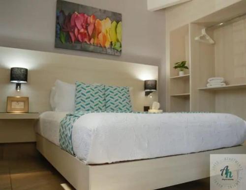 ein Schlafzimmer mit einem großen weißen Bett mit einem Gemälde an der Wand in der Unterkunft B - Céntrico Loft Privado - Alegría Housing in Aguascalientes