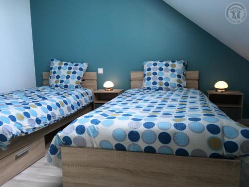 two beds in a bedroom with blue walls and two lamps at Maison Douaisis pour 4 pers avec jardin, terrasse, parking sécurisé et proche tramway - FR-1-510-134 in Aniche