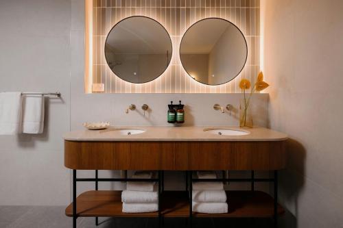 a bathroom with two sinks and two mirrors at Crowne Plaza Adelaide Mawson Lakes by IHG in Adelaide