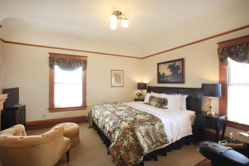 a bedroom with a bed and a chair and windows at The Charles Pacific Grove in Pacific Grove