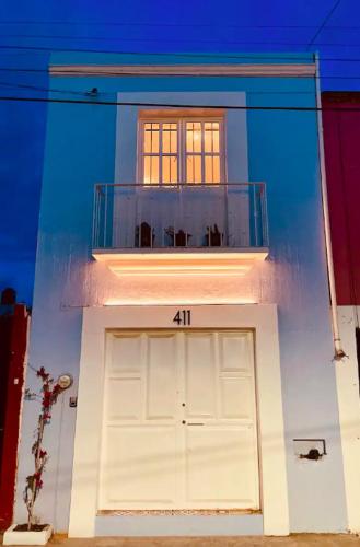 a white building with a large door with the number at Bugambilia Azul Centro Oaxaca in Oaxaca City