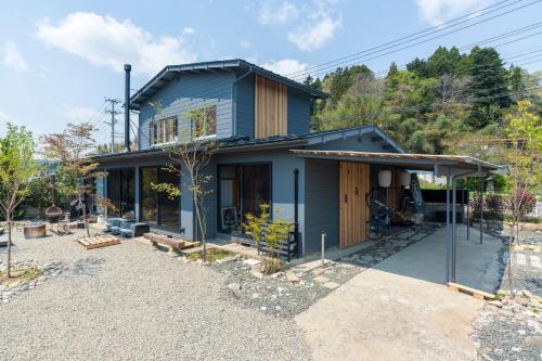 a blue house in the middle of a yard at 薪ストーブの古民家一軒宿アゼミチタベネル in Shimo-ayashi