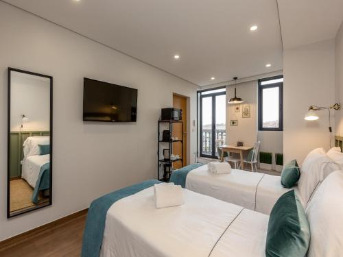 a hotel room with two beds and a mirror at Feel Porto Wine Essence IV in Vila Nova de Gaia