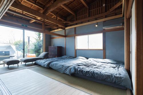 a bedroom with a bed and a large window at 薪ストーブの古民家一軒宿アゼミチタベネル in Shimo-ayashi