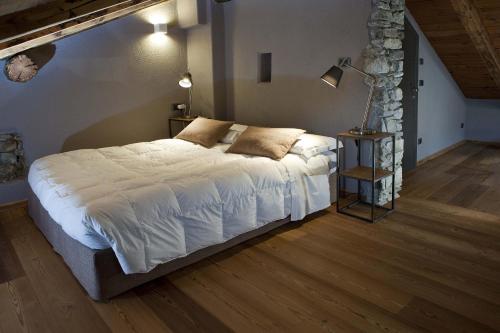 una camera da letto con un grande letto con lenzuola bianche di Guesthouse Mu ad Aosta