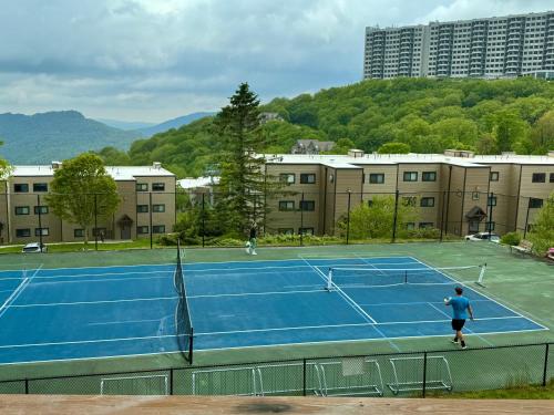 a man playing tennis on a tennis court at The Sugar Suite - Renovated with a View! Ski IN-OUT! Heated POOL, Hot tub, sauna, gym, AC, EV in Sugar Mountain