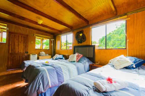 three beds in a room with wooden walls and windows at Cabañas Moai in Hanga Roa