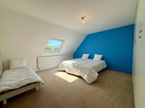 une chambre avec deux lits et un mur bleu dans l'établissement Maison spacieuse à Carnac, 6 pièces, 8 personnes, grand jardin, 300m du centre - FR-1-377-101, à Carnac