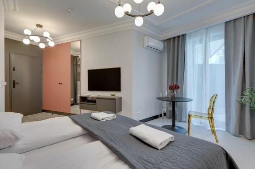 een slaapkamer met een bed, een televisie en een tafel bij Żurawie IKONY 2 by Grand Apartments in Gdańsk