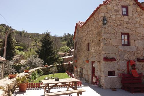 ein Steingebäude mit einem Tisch und Bänken davor in der Unterkunft Casas da Fonte - Serra da Estrela in Seia