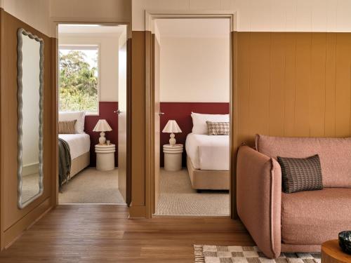 a bedroom with two beds and a couch and a mirror at The Isla & Casita in Batemans Bay