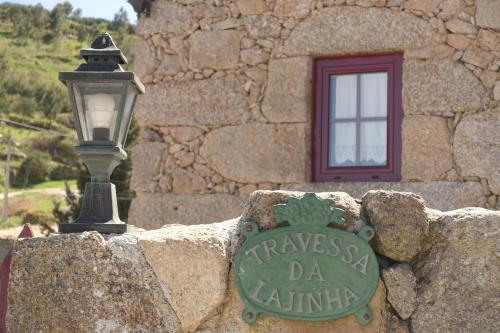 um sinal numa parede de pedra ao lado de uma luz de rua em Casas da Fonte - Serra da Estrela em Seia