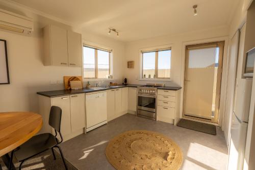 a kitchen with white cabinets and a wooden table at Relax on Rata, Cottage 2 in Twizel
