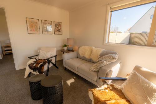 a living room with a couch and a window at Relax on Rata, Cottage 2 in Twizel