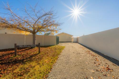 a pathway with a tree next to a fence at Relax on Rata, Cottage 2 in Twizel