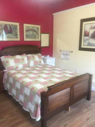a bedroom with a bed with a red wall at Appartement du Moulin in L'Isle-aux-Coudres
