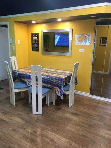 a dining room table with chairs and a yellow wall at Appartement du Moulin in L'Isle-aux-Coudres