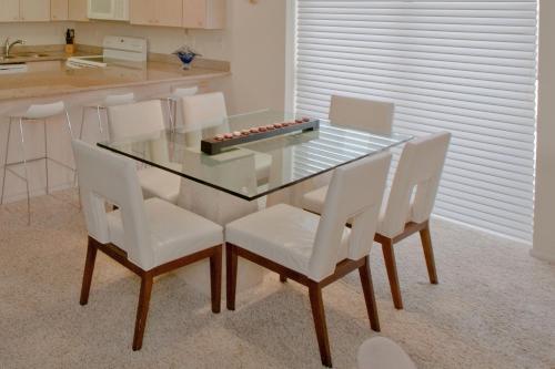 a glass table with white chairs and a kitchen at Sea Vista in South Padre Island