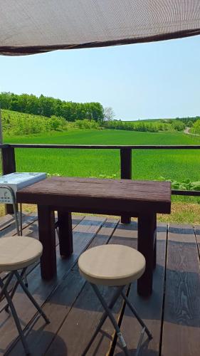 a wooden table and two chairs on a deck with a view at Bears Cottages in Furano