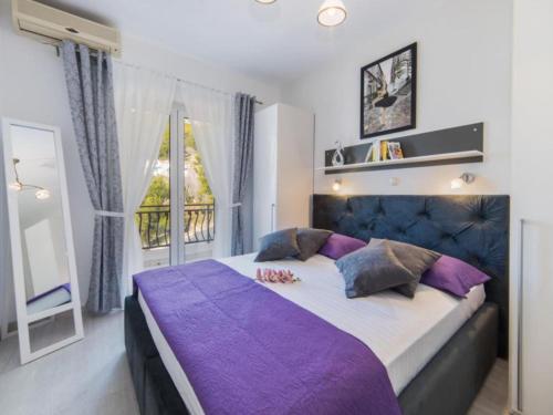 a bedroom with a large bed with purple sheets and a window at Apartments Tafra - One Bedroom Apartment in Lokva Rogoznica