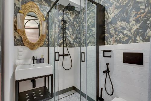a bathroom with a shower with a sink and a mirror at Żurawie by Grand Apartments in Gdańsk