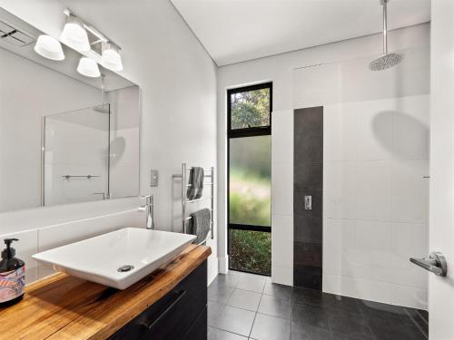 a white bathroom with a sink and a mirror at Wildflower Ridge in Yallingup