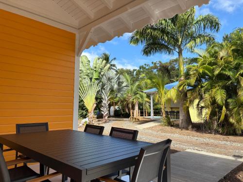a wooden table and chairs on a porch with palm trees at Le Paradis de la Guadeloupe in Pointe-Noire