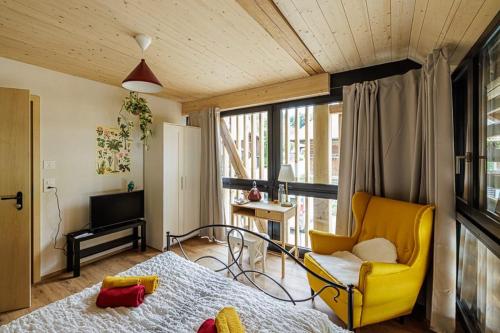 a room with a bed and a yellow chair at Gruppenunterkunft mit Billardtisch und Lamatrekking in Meikirch