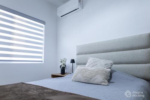 a white bedroom with a bed and a window at R - Casa Privada - Alegria Housing in Aguascalientes