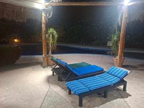two blue lounge chairs next to a pool at night at Diana 28 in Jarretadera