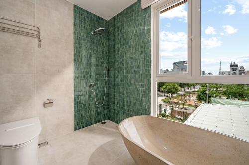 a bathroom with a tub and a window and green tiles at Kochi House, brand new 4BDR, 850m to the beach in Da Nang