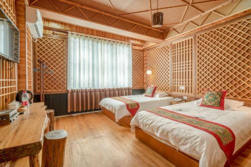 a hotel room with two beds and a desk at Longsheng Longji Rice Terraces Jingyue Hotel 龙胜龙脊梯田境悦酒店 in Longsheng