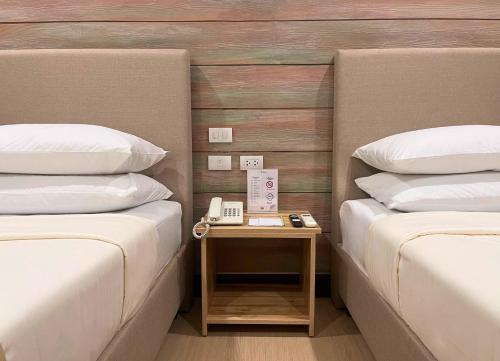 a room with two beds and a table with a phone at Sola Hotel and Sola Bed & Breakfast in Laoag