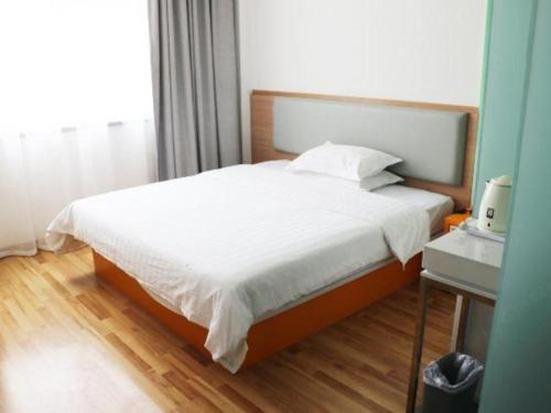 a bedroom with a large bed with white sheets at 7Days Inn Tianjin Airport NO.1 Bridge Branch in Tianjin