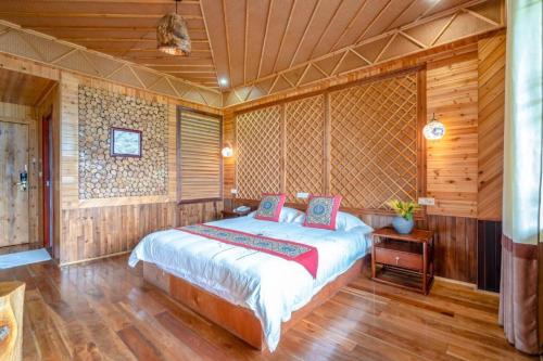 a bedroom with a bed in a room with wooden walls at Longsheng Longji Rice Terraces Jingyue Hotel 龙胜龙脊梯田境悦酒店 in Longsheng