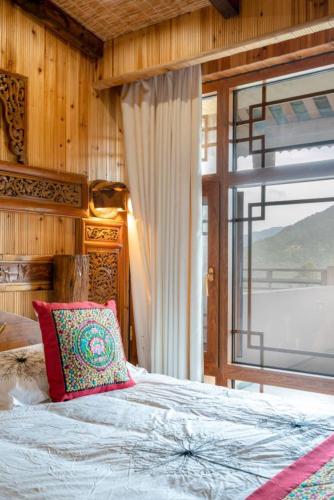 a bedroom with a bed and a large window at Longsheng Longji Rice Terraces Jingyue Hotel 龙胜龙脊梯田境悦酒店 in Longsheng