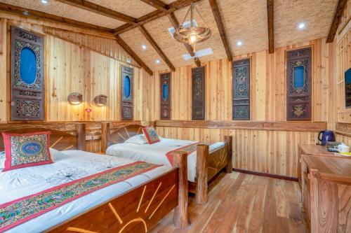 two beds in a room with wooden walls at Longsheng Longji Rice Terraces Jingyue Hotel 龙胜龙脊梯田境悦酒店 in Longsheng